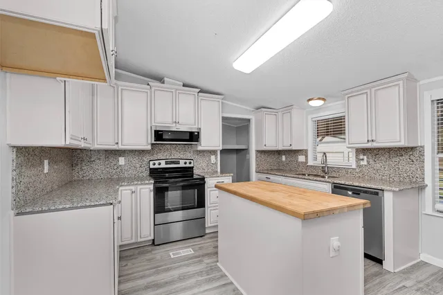 a kitchen with stainless steel appliances granite countertop a sink stove and refrigerator