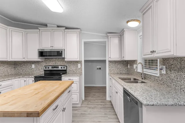 a kitchen with stainless steel appliances granite countertop a kitchen island a stove a sink and a microwave