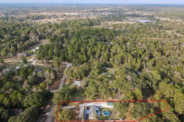 an aerial view of a house with backyard space and trees