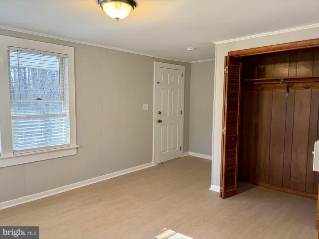 a view of an empty room with window and a bedroom