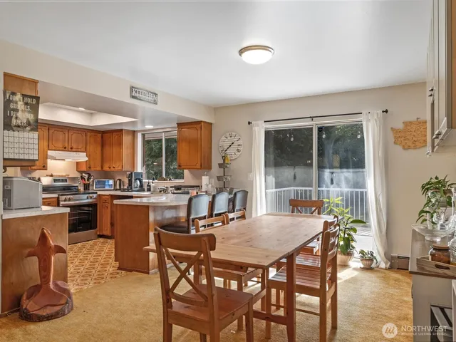 a dining room with furniture a kitchen view and large windows