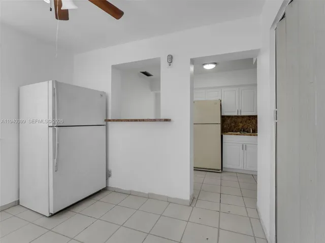 a kitchen with a refrigerator and white cabinets