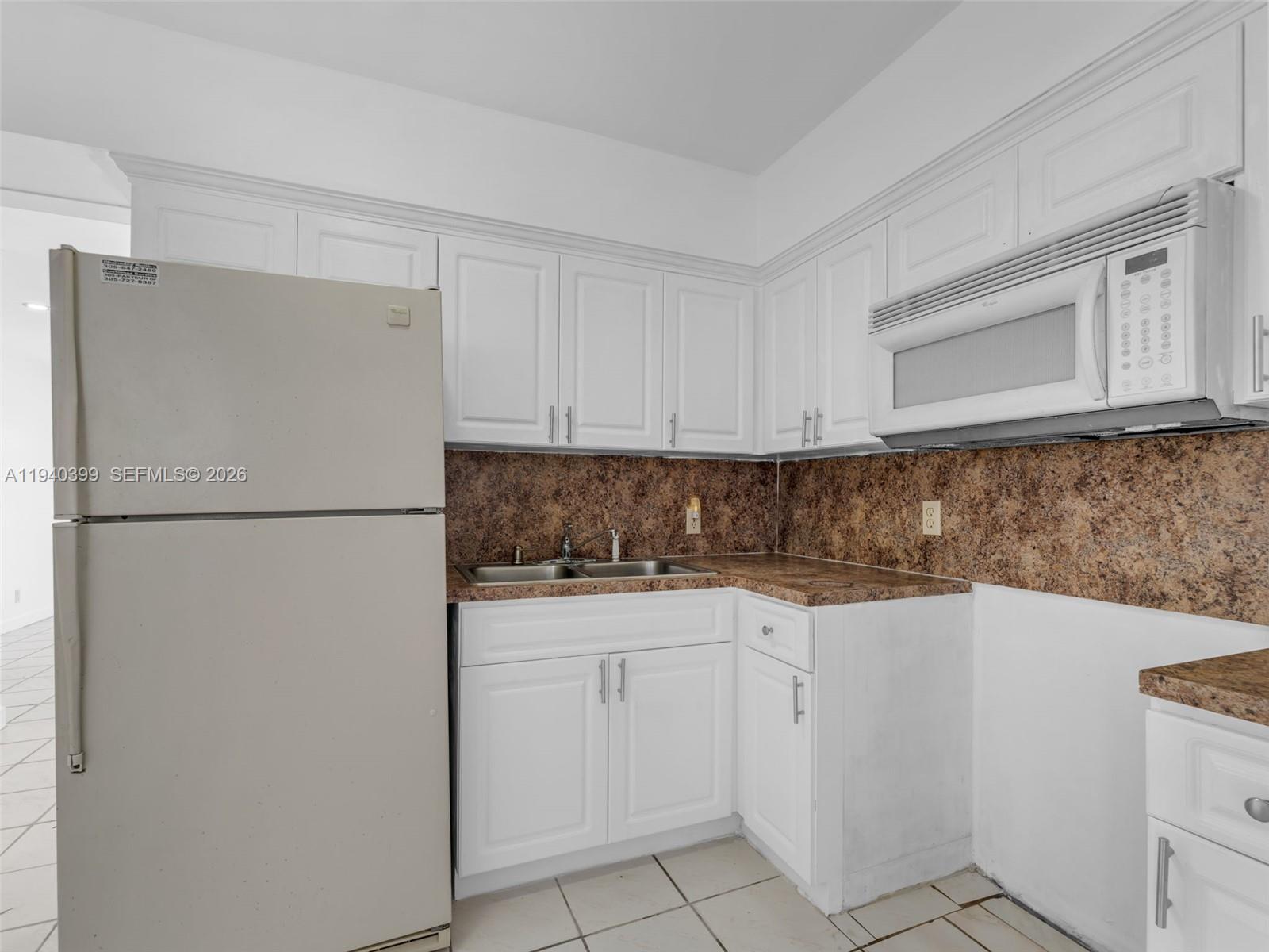 1811 Southwest 97th Terrace, Unit 2 Miramar, FL 33025 - Photo 21 of 29 a kitchen with white cabinets and refrigerator