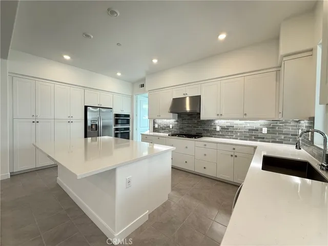 a large white kitchen with stainless steel appliances