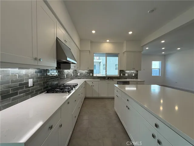 a large kitchen with stainless steel appliances a sink a stove and cabinets