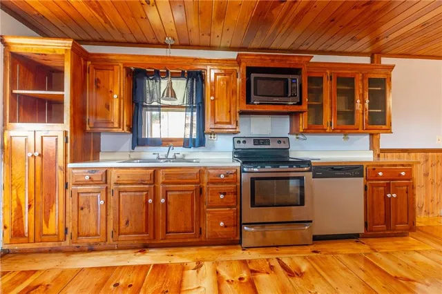 a kitchen with stainless steel appliances granite countertop wooden cabinets a stove top oven a sink and dishwasher