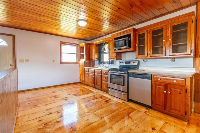 a large kitchen with stainless steel appliances wooden cabinets a stove and a refrigerator