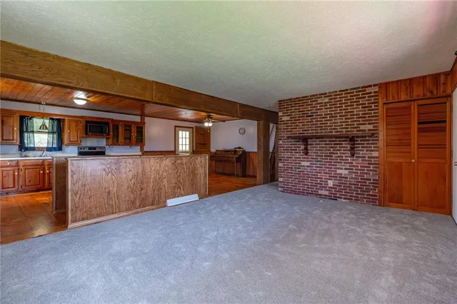 a view of an empty room with furniture and kitchen view