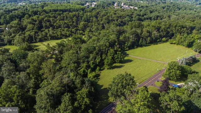 an aerial view of a residential houses with outdoor space and trees all around