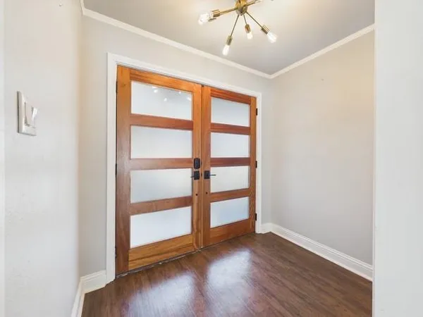 an empty room with wooden floor chandelier and windows