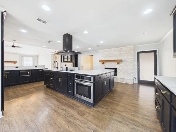 a large kitchen with stainless steel appliances a large counter top a stove and a sink