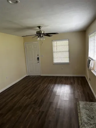 an empty room with wooden floor cabinet and windows