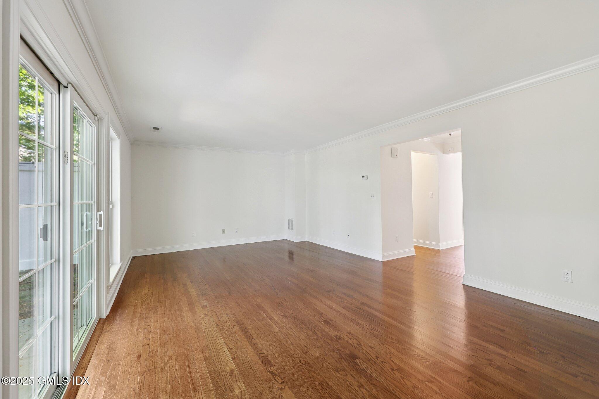 251 Weaver Street, Unit 1C Greenwich, CT 06831 - Photo 11 of 29 a view of an empty room with wooden floor and a window