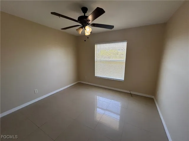 an empty room with a window and a fan