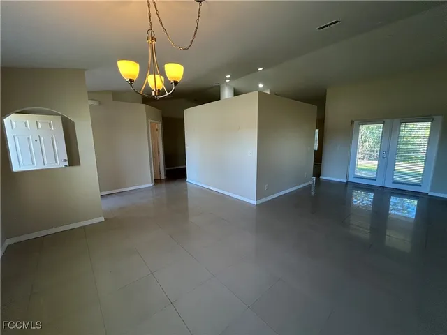 a view of an empty room with window and chandelier