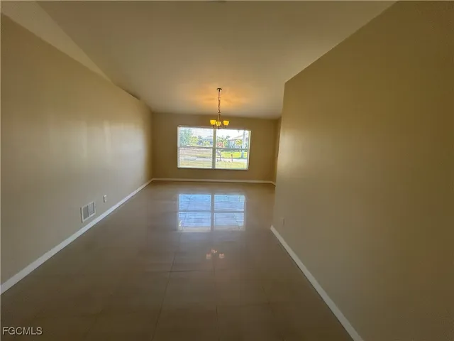 an empty room with windows and chandelier fan
