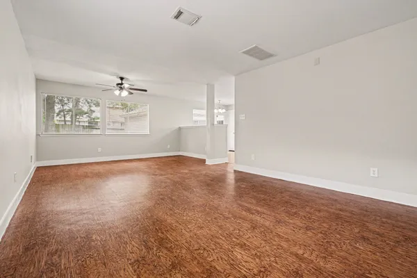 an empty room with wooden floor and window
