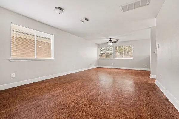an empty room with wooden floor and windows