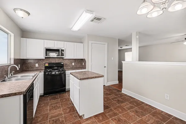 a kitchen with granite countertop a sink stove and refrigerator