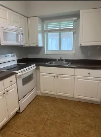 a kitchen with granite countertop white cabinets and white appliances