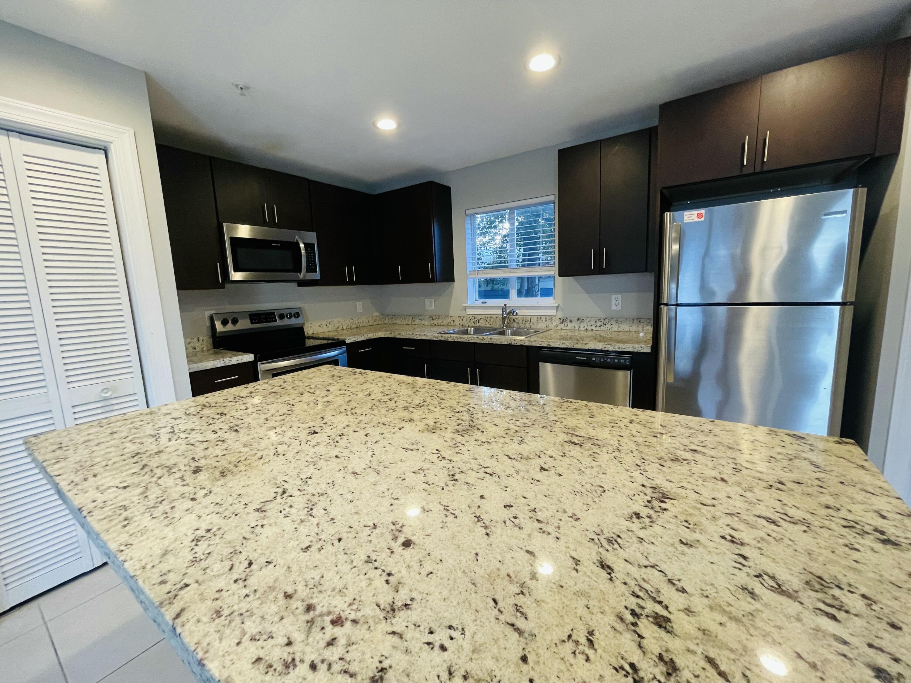 102940 Overseas Highway, Unit 2 Key Largo, FL 33037 - Photo 23 of 39 a kitchen with kitchen island a sink stainless steel appliances and counter space