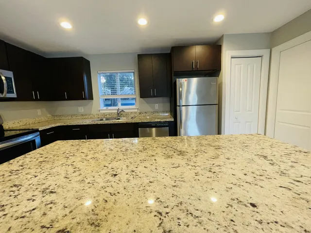 a kitchen with stainless steel appliances granite countertop refrigerator stove top oven a sink and dishwasher