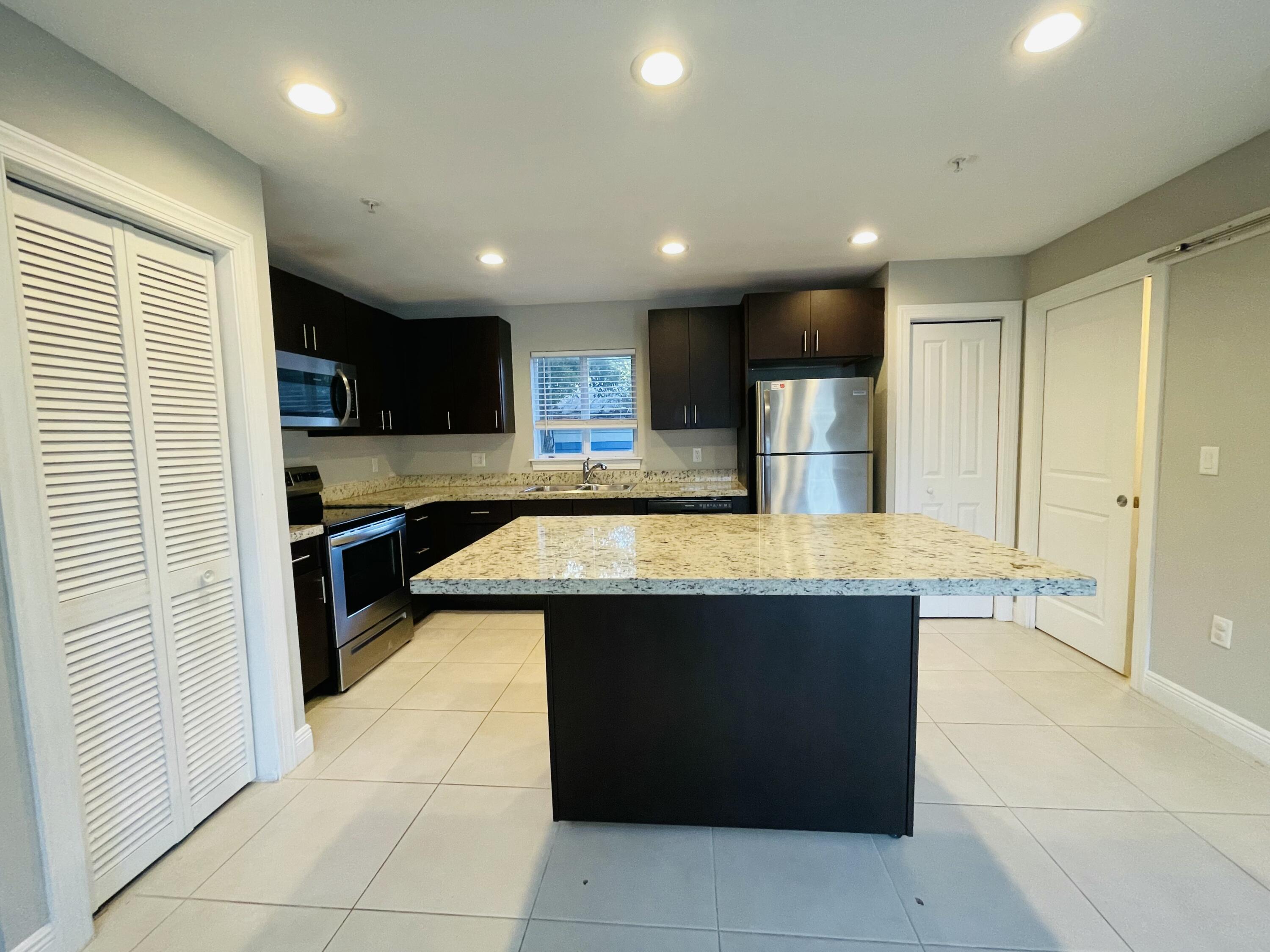 102940 Overseas Highway, Unit 2 Key Largo, FL 33037 - Photo 25 of 39 a kitchen with kitchen island granite countertop wooden cabinets a sink and a stove