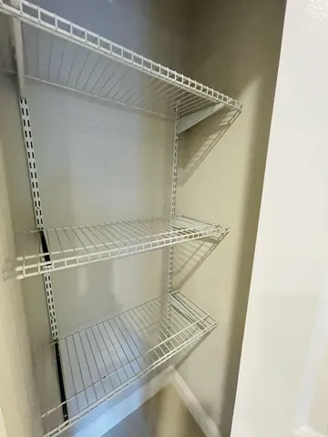 a view of an empty room with window and chandelier fan