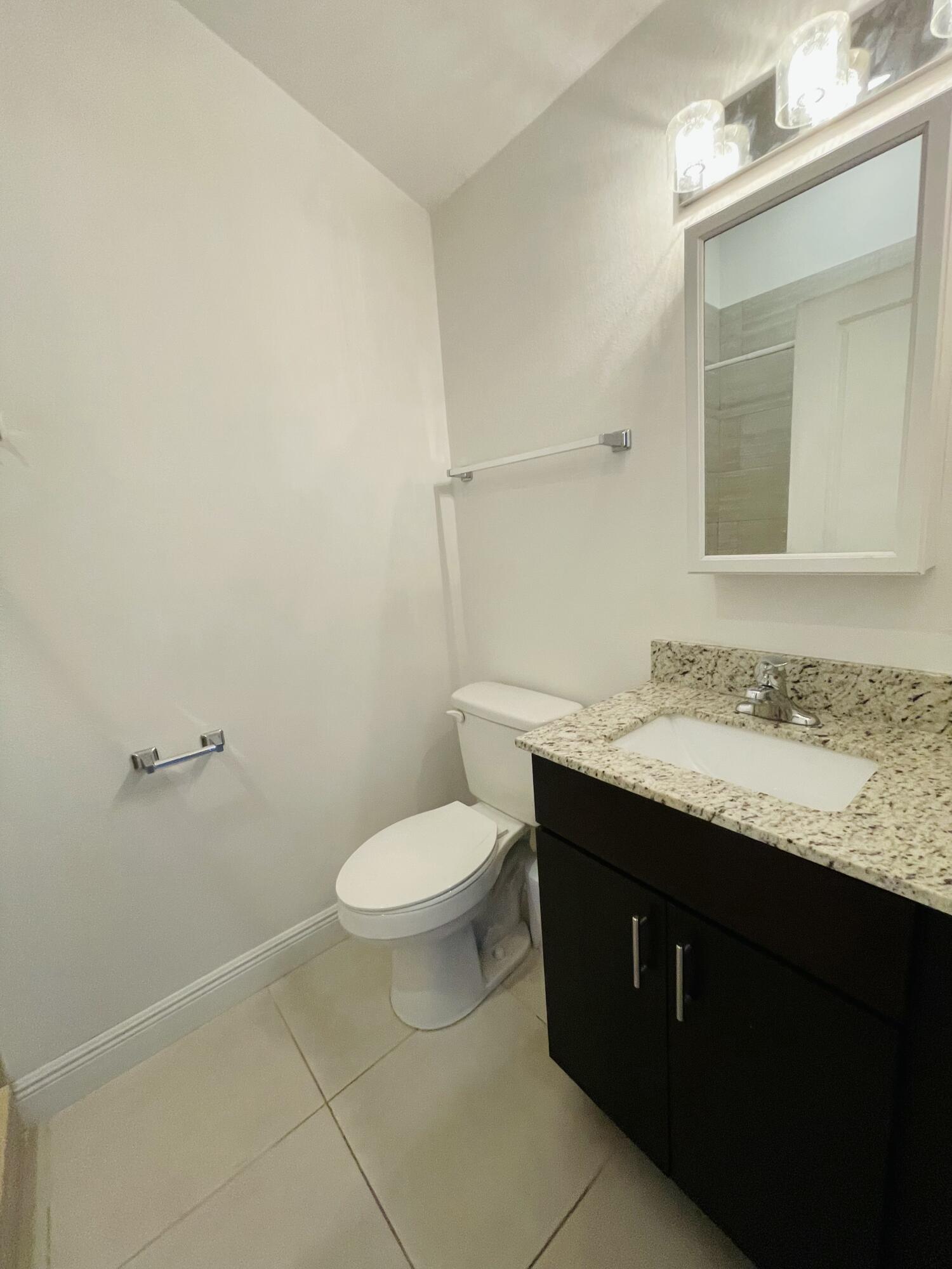 102940 Overseas Highway, Unit 2 Key Largo, FL 33037 - Photo 39 of 39 a bathroom with a granite countertop sink toilet and mirror