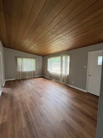 a view of an empty room with wooden floor and window
