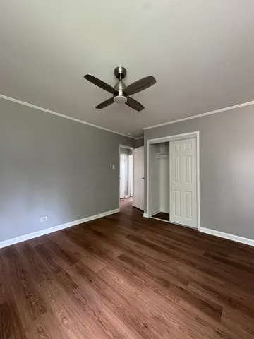 a view of an empty room with wooden floor and a ceiling fan