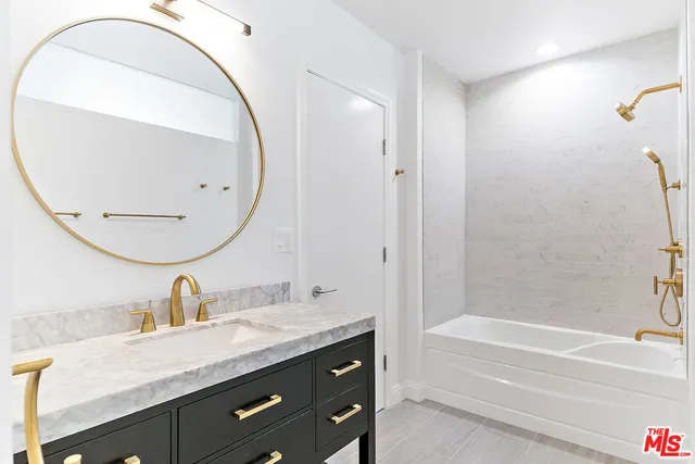 a bathroom with a granite countertop sink a mirror and a bathtub