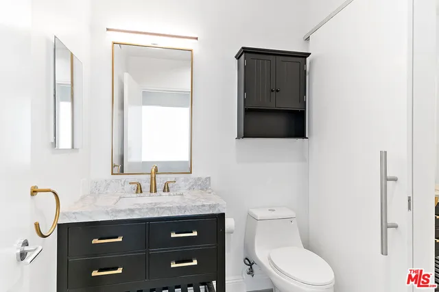 a bathroom with a granite countertop toilet sink and mirror
