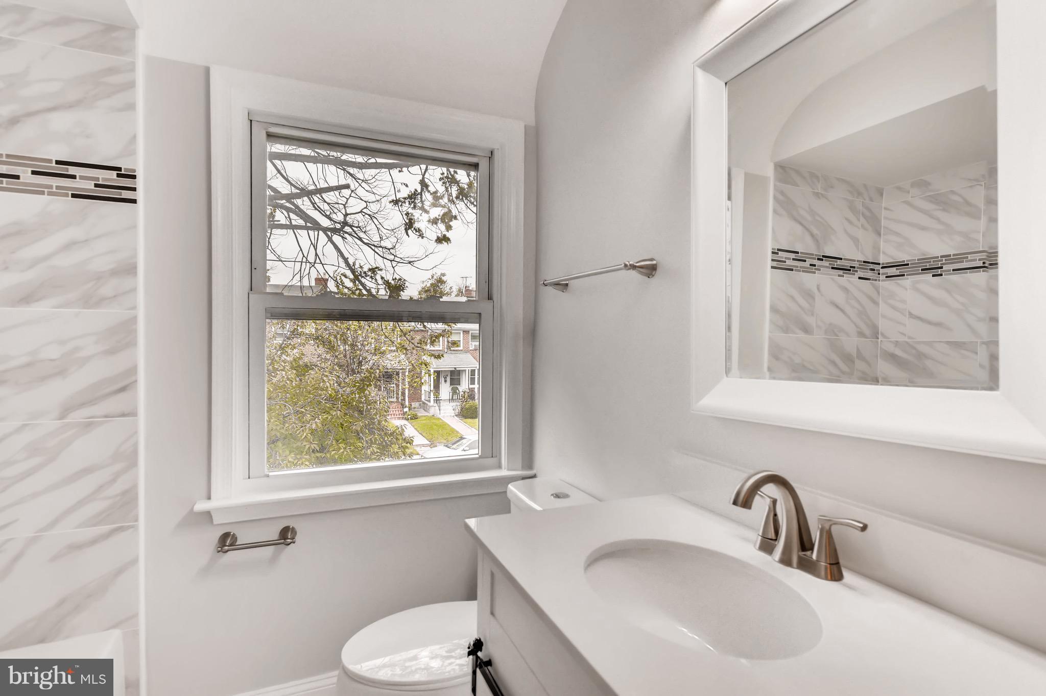 1315 Silverthorne Road Baltimore, MD 21239 - Photo 13 of 28 a bathroom with a sink a toilet and a window
