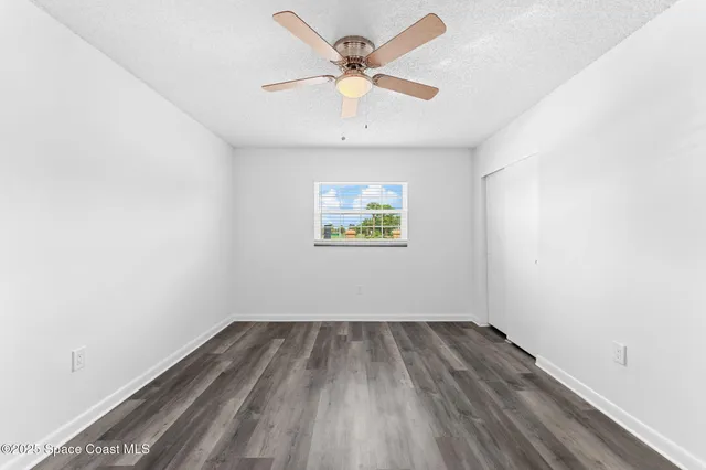 an empty room with a window and a ceiling fan