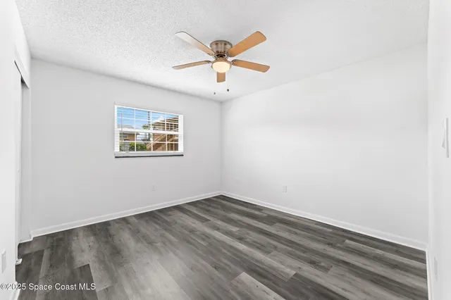 an empty room with wooden floor and ceiling fan