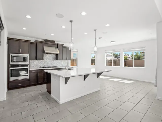 a large white kitchen with a stove a sink a microwave and a refrigerator