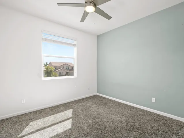 an empty room with a ceiling fan and carpet