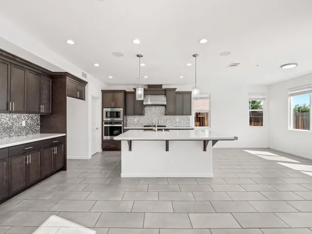 a large kitchen with kitchen island a sink a stove a center island stainless steel appliances and a window