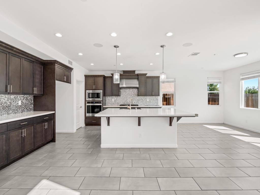 3438 Lincoln Avenue Clovis, CA 93619 - Photo 9 of 52 a large kitchen with kitchen island a sink a stove a center island stainless steel appliances and a window