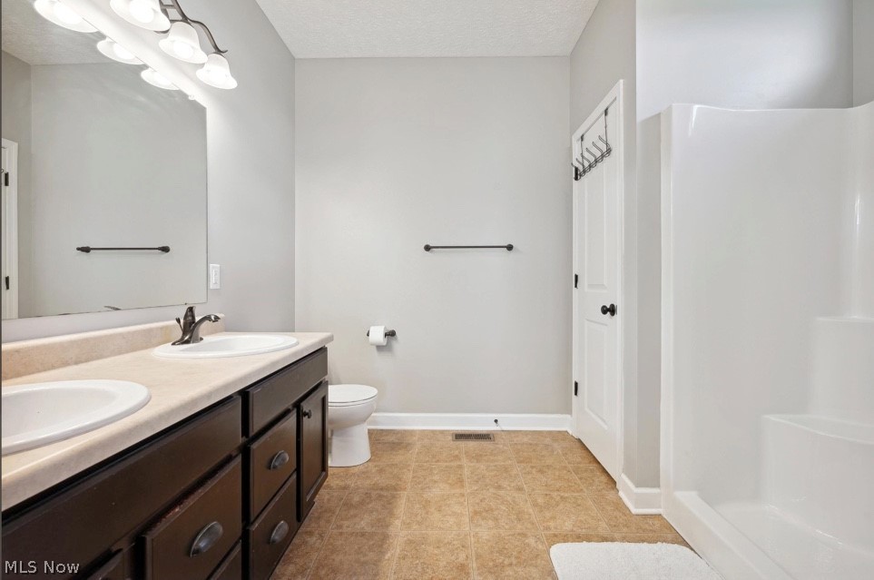 405 East Luchsinger Road Port Clinton, OH 43452 - Photo 20 of 40 Bathroom with tile flooring, toilet, double vanity, a textured ceiling, and walk in shower
