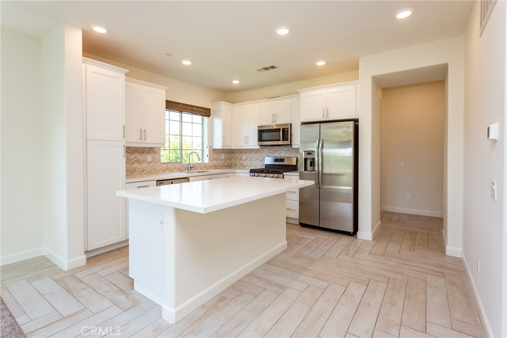 4366 Pacifica Way, Unit 6 Oceanside, CA 92056 - Photo 5 of 25 a kitchen with a refrigerator a sink and a stove top oven with wooden floor