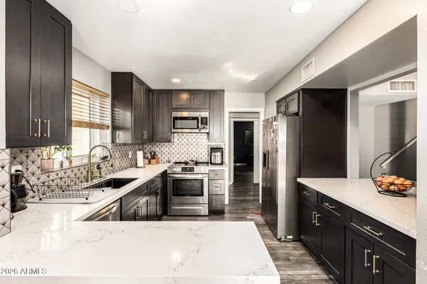 a kitchen with stainless steel appliances granite countertop a sink stove and refrigerator