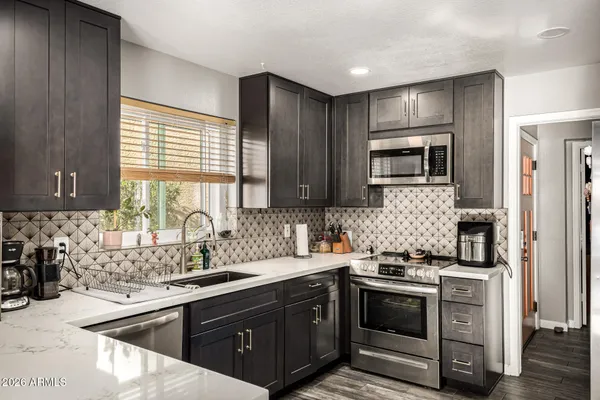 a kitchen with stainless steel appliances granite countertop a sink stove microwave and refrigerator