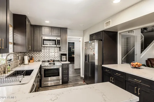 a kitchen with stainless steel appliances kitchen island granite countertop a refrigerator stove and sink