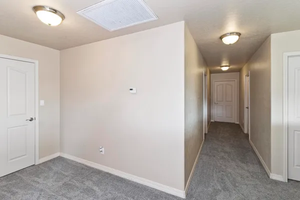 an empty room with windows and chandelier fan