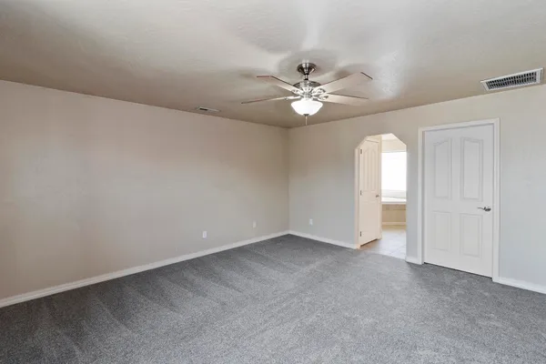 an empty room with windows and chandelier fan