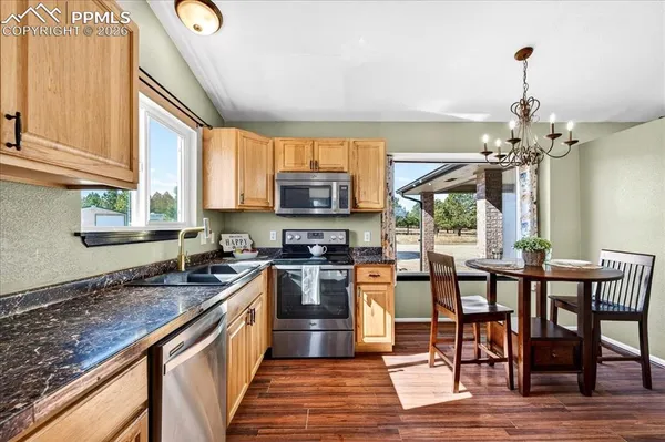 a kitchen with granite countertop a stove top oven a sink dishwasher a dining table and chairs with wooden floor