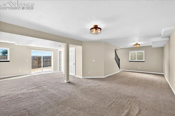 an empty room with windows and fireplace