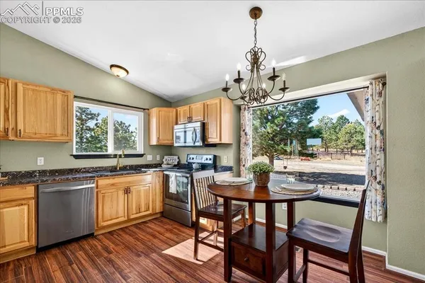 a kitchen with stainless steel appliances granite countertop wooden floor dining table and chairs